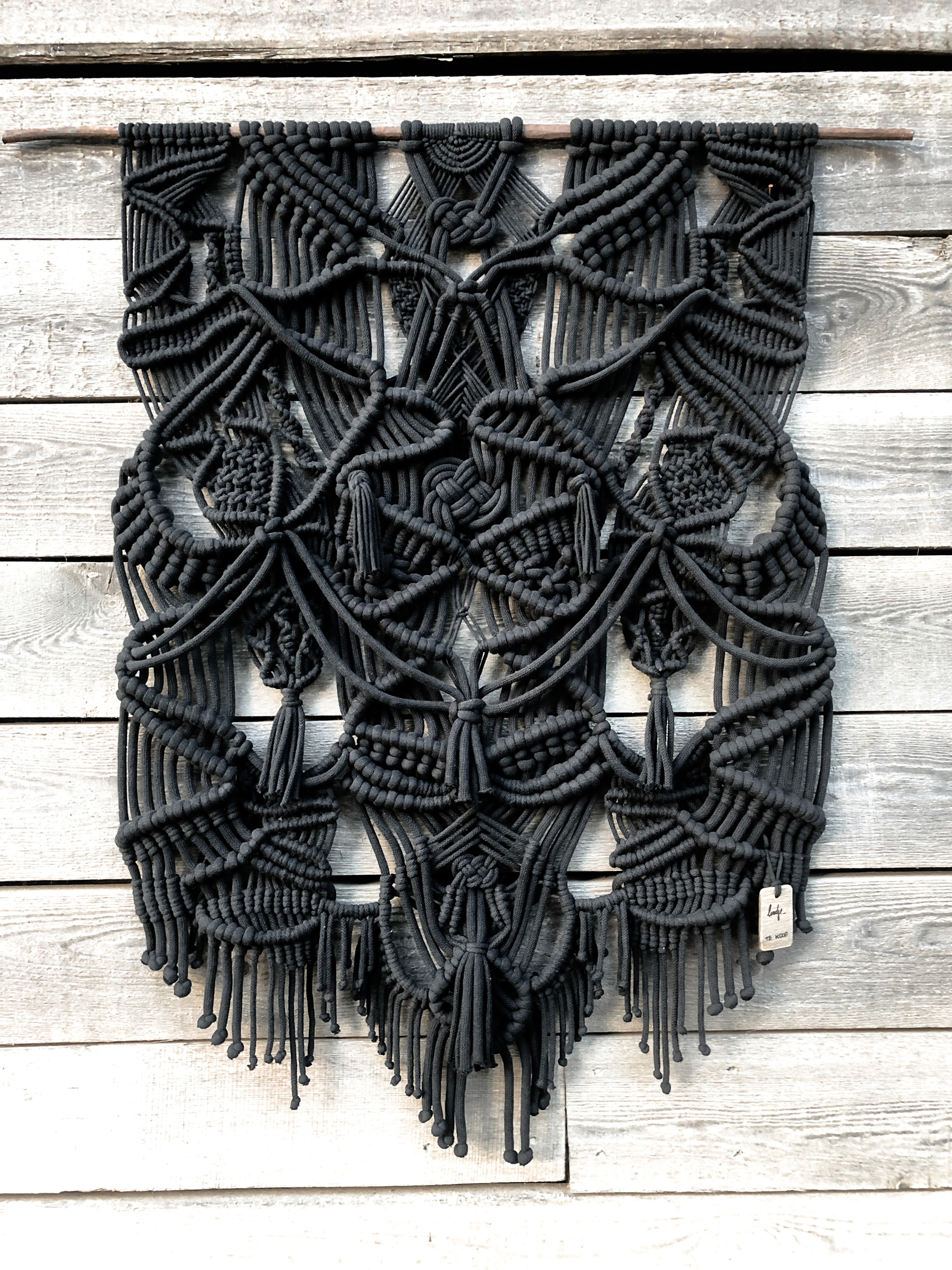 large black modern handmade macrame wallhanging on rustic wooden boards